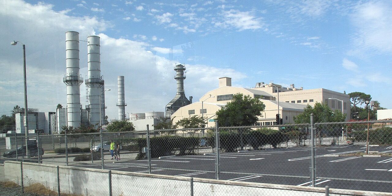 Exhaust stacks of a natural gas-fired power plant against a blue sky.