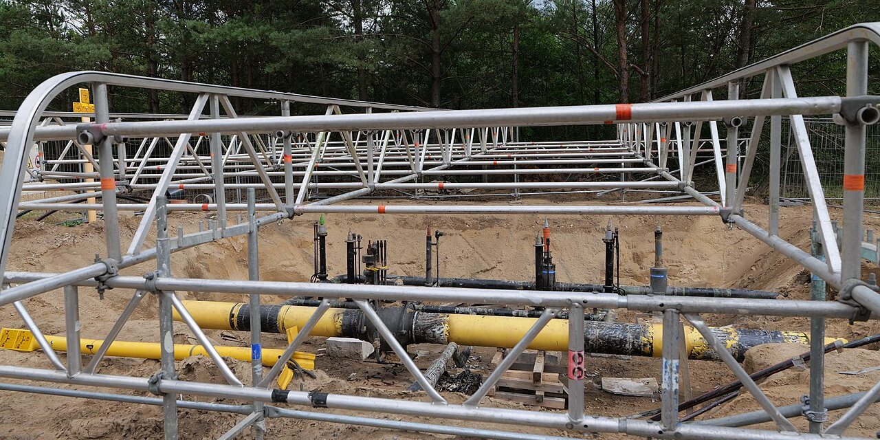 A yellow natural gas pipeline being laid in an open trench.