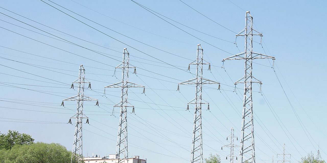 Steel lattice transmission towers carrying high-voltage lines over open ground.